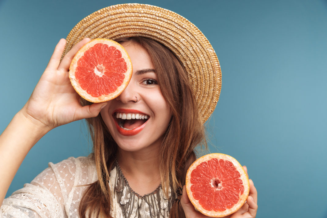 Молодая счастливая девушка с грейпфрутом