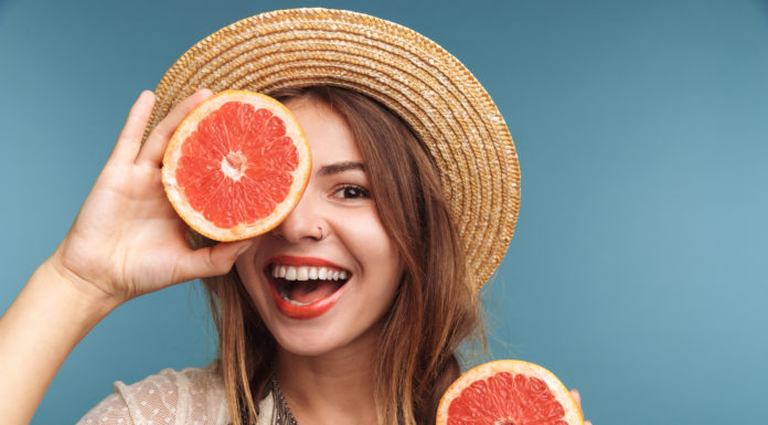 Молодая счастливая девушка с грейпфрутом