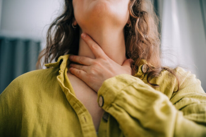 Woman suffering from sore throat holding her neck