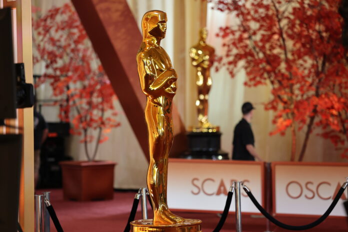 Workers polish a decorative Oscar statue on the red carpet during preparations for Sunday night's Academy Awards ceremony held at the Dolby Theatre